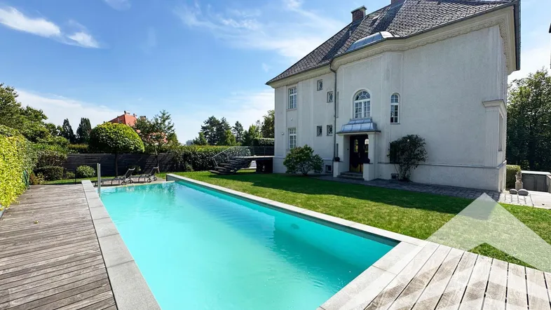 Großzügiger Außenbereich mit langem Swimmingpool, Holzdeck und gepflegtem Rasen vor der Villa.