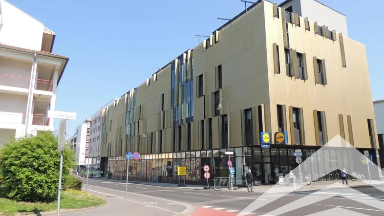 Modernes Geschäftsgebäude mit goldener Fassade und großen Schaufenstern an einer Straßenecke.