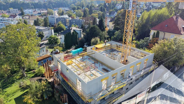 Luftaufnahme einer Baustelle mit einem Kran, der ein neues Gebäude in einer Wohngegend errichtet.