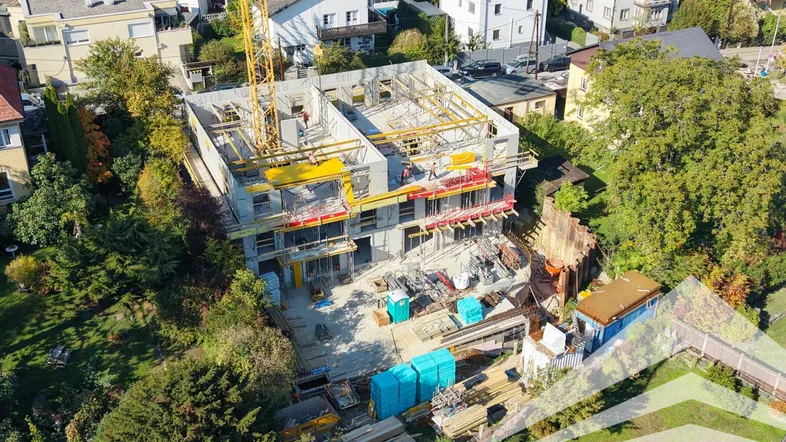 Luftaufnahme einer Baustelle mit Kran und im Bau befindlichen Gebäuden in städtischer Umgebung.