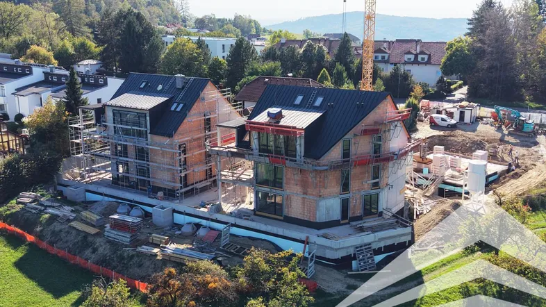 Luftaufnahme von zwei im Bau befindlichen Gebäuden mit Gerüsten und einem Kran.