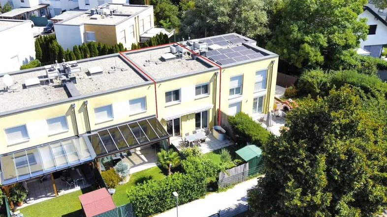 Luftaufnahme von Reihenhäusern mit Gärten und Solaranlagen auf den Dächern in einer Wohnsiedlung.