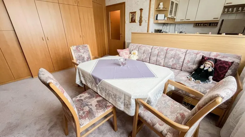 Gemütlicher Wohn-Essbereich mit integrierter Küche, Holzmöbeln und Teppichboden in traditionellem Stil.