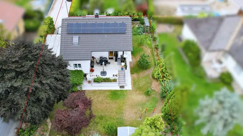 Luftaufnahme des Hauses mit Photovoltaikanlage auf dem Dach und großem Gartenbereich.