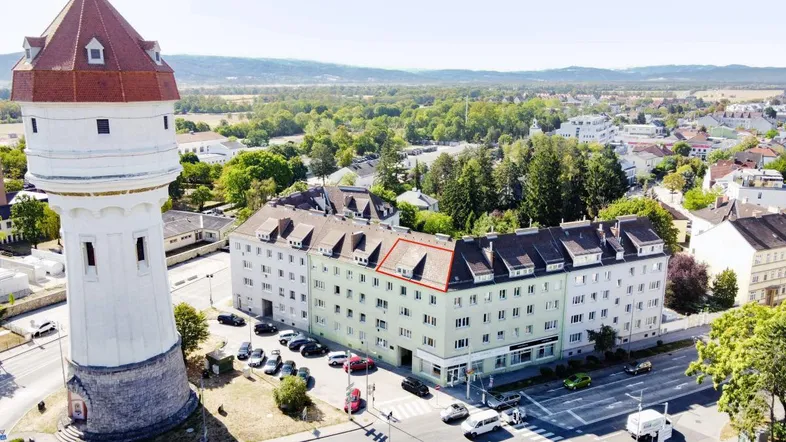 Luftaufnahme eines Wohngebäudes mit roter Umrandung und einem markanten Wasserturm in städtischer Umgebung.