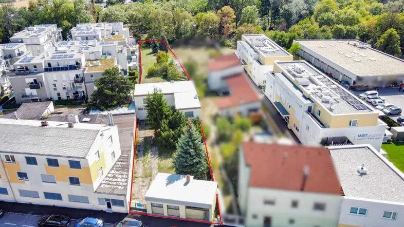 Luftaufnahme eines Grundstücks mit roter Umrandung, umgeben von Wohngebäuden und Bäumen.