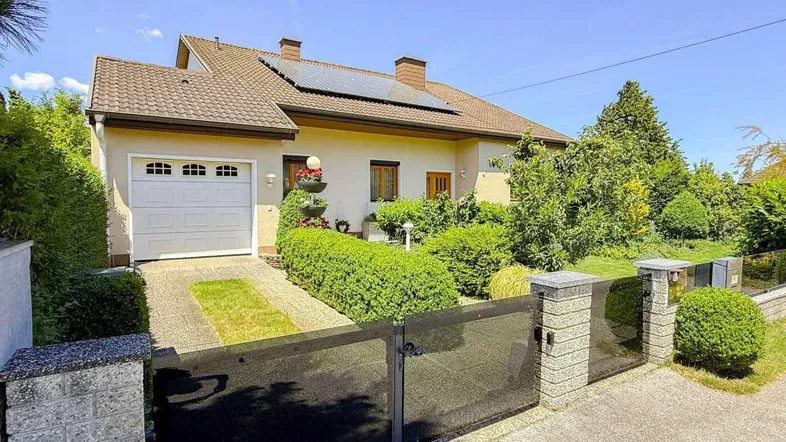 Einfamilienhaus mit gepflegtem Vorgarten, Garage und Solaranlage auf dem Dach.