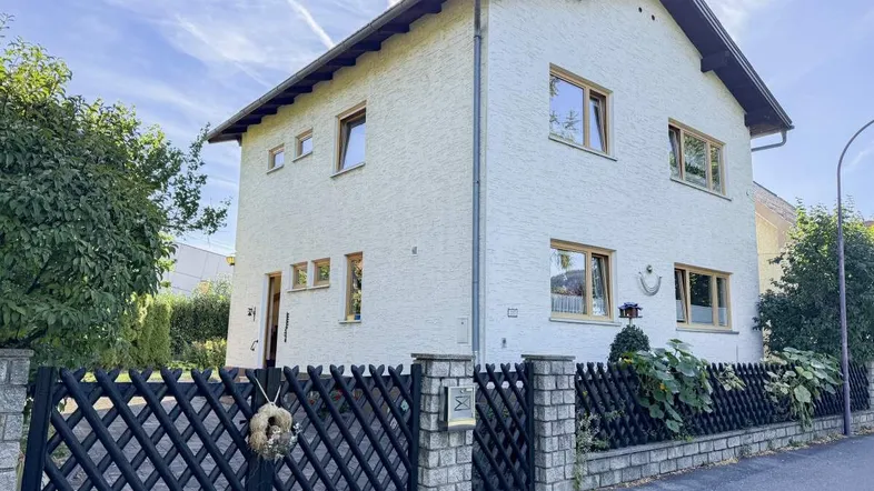 Freistehendes Einfamilienhaus mit heller Fassade und gepflegtem Vorgarten, umgeben von Grün.