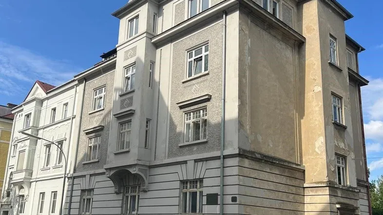 Historisches Mehrfamilienhaus mit klassischer Architektur und sichtbaren Gebrauchsspuren an der Fassade.