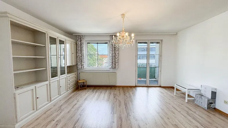 Helles Wohnzimmer mit Laminatboden, Einbauschrank und Zugang zum Balkon.