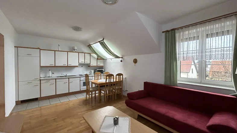 Helles Dachgeschoss-Apartment mit offener Küche, Essbereich und Wohnzimmer, ausgestattet mit Holzboden.
