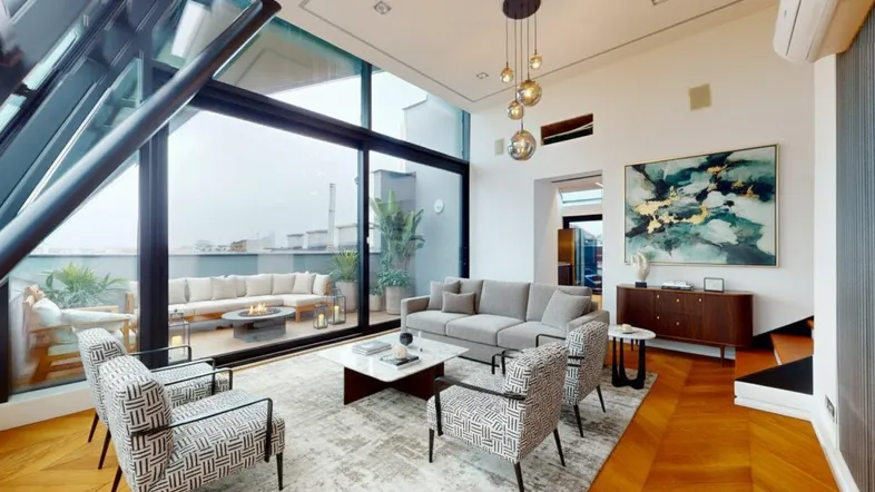 Modernes Wohnzimmer mit Fischgrätparkett, großen Fenstern und Zugang zu einer möblierten Dachterrasse.