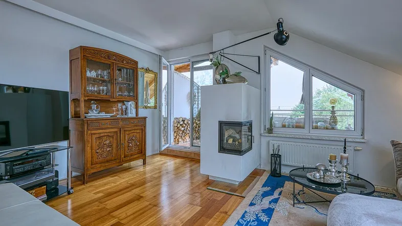 Helles Wohnzimmer mit Holzboden, Kamin und Zugang zu einem Außenbereich mit Holzstapel.