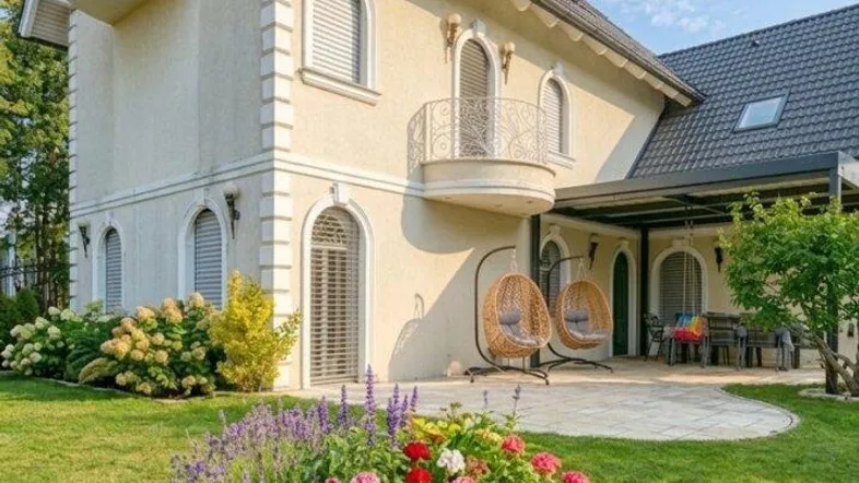 Elegantes Haus mit gepflegtem Garten, Blumenbeeten und einer Terrasse mit Hängesesseln.