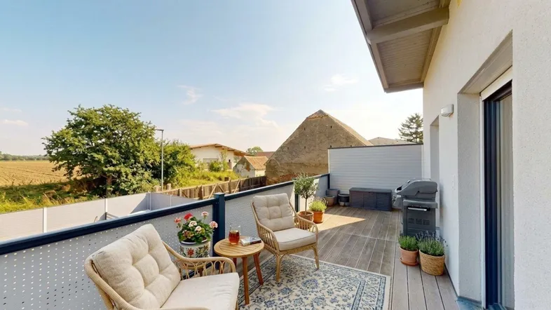 Geräumiger Balkon mit Sitzgelegenheiten, Grill und weitem Blick über die Landschaft.