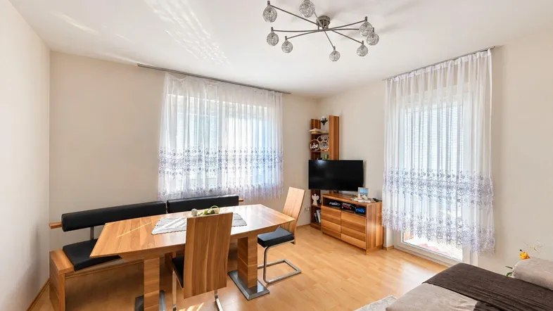 Heller Wohn- und Essbereich mit Holztisch, bequemer Sitzbank und Parkettboden, ideal für gesellige Stunden.