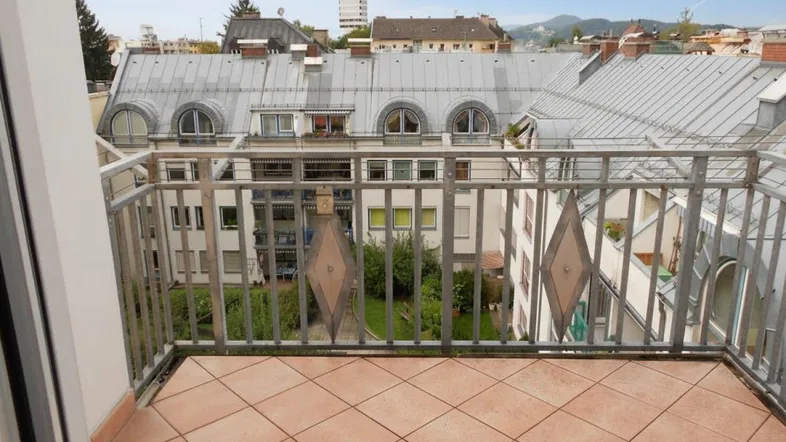 Balkon mit Fliesenboden und Metallgeländer bietet einen weiten Blick über die Dächer der Stadt.