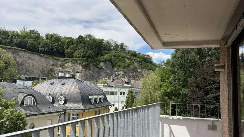 Geräumiger Balkon mit Holzboden und weitem Blick ins Grüne sowie auf die umliegenden Gebäude.
