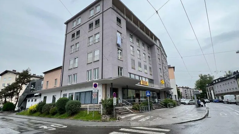 Gebäude an einer Straßenecke mit moderner Architektur und großen Fenstern im Stadtgebiet.