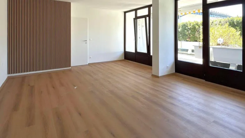 Helles Wohnzimmer mit modernem Holzlamellen-Akzent, Holzboden und Zugang zum Außenbereich.