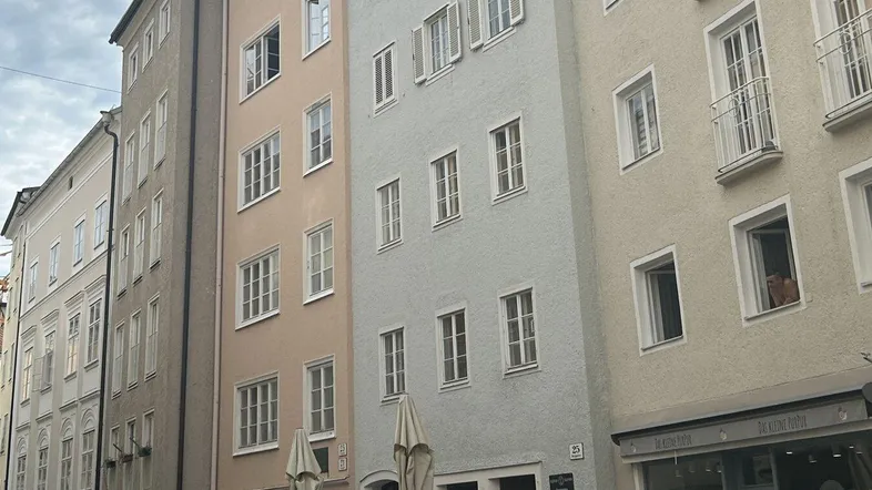 Historische Gebäudezeile mit traditionellen Fassaden, Fenstern und kleinen Balkonen in einer Stadtstraße.