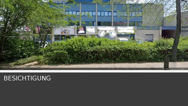 Außenansicht eines modernen Geschäftsgebäudes mit blauer Fassade und umgebender Vegetation.