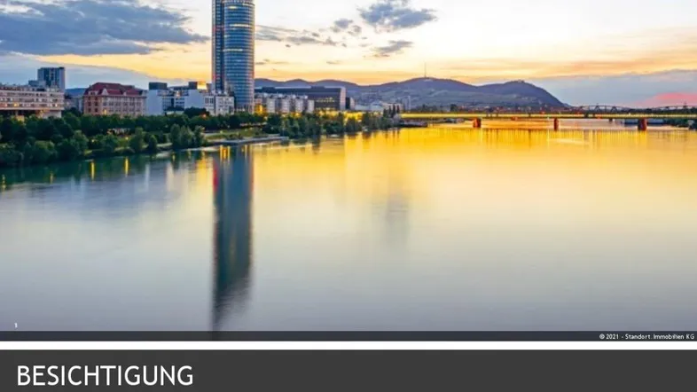 Panoramablick auf die Donau mit der Skyline von Wien und einem markanten Hochhaus bei Sonnenuntergang.