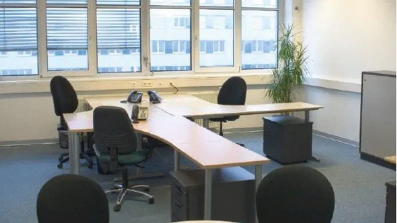 Geräumiges Büro mit mehreren Arbeitsplätzen, großen Fenstern und Teppichboden für eine produktive Umgebung.