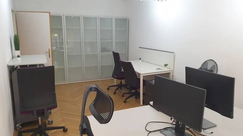 Modernes Büro mit mehreren Arbeitsplätzen, Schränken und Parkettboden, ideal für ein Team.