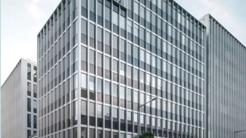 Modernes Bürogebäude mit Glasfassade und Einzelhandelsgeschäft im Erdgeschoss in urbaner Umgebung.