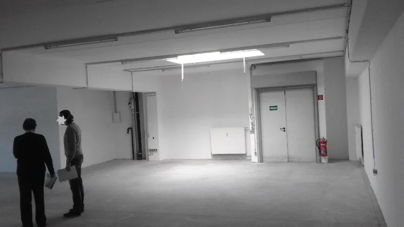 Geräumiger, leerer Gewerberaum mit hohen Decken und Oberlicht, bereit für den Ausbau.