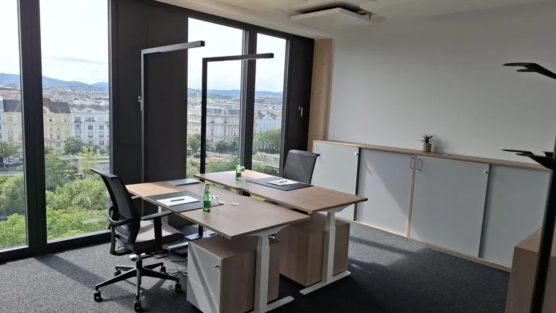 Modernes Büro mit großen Fenstern, die einen weiten Blick auf die Stadt und Grünflächen bieten.