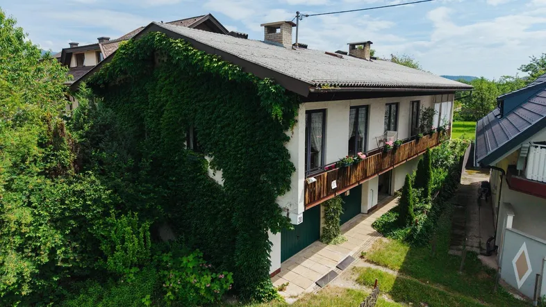 Traditionelles Haus mit Efeubewuchs an der Fassade und einem Balkon im Obergeschoss.
