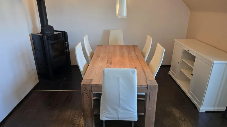 Geräumiger Essbereich mit Holztisch, modernen Stühlen und einem gemütlichen Kaminofen.