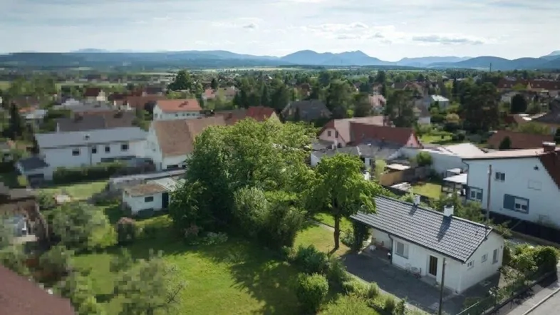 Luftaufnahme der Wohngegend mit Blick auf das Einfamilienhaus und die umliegende Landschaft mit Bergen.