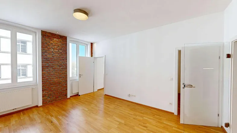 Helles Zimmer mit Holzboden und einer Akzentwand aus Ziegeln, bereit zur individuellen Gestaltung.