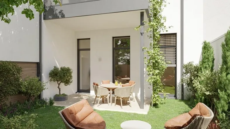 Moderne Terrasse mit Gartenmöbeln und Rasenfläche, umgeben von Grünpflanzen und einem Neubau.