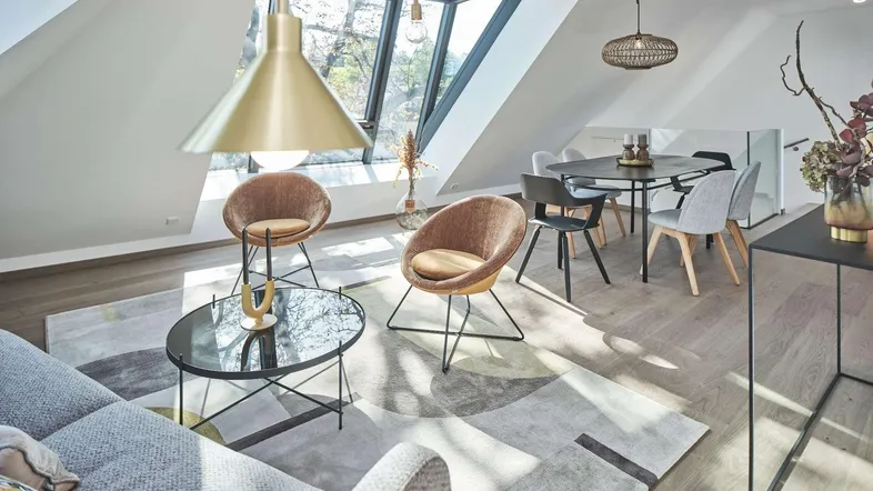 Helles, offenes Wohn-Esszimmer mit modernen Möbeln, Holzboden und großen Dachfenstern für viel Tageslicht.