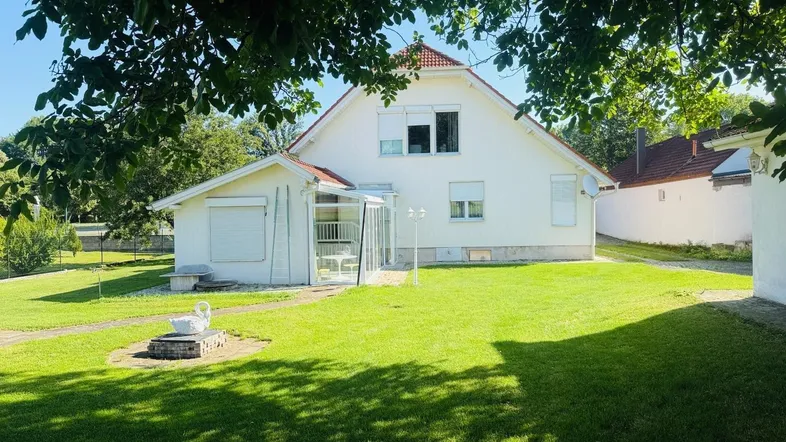 Rückansicht des Hauses mit Wintergarten und großem, gepflegten Garten.