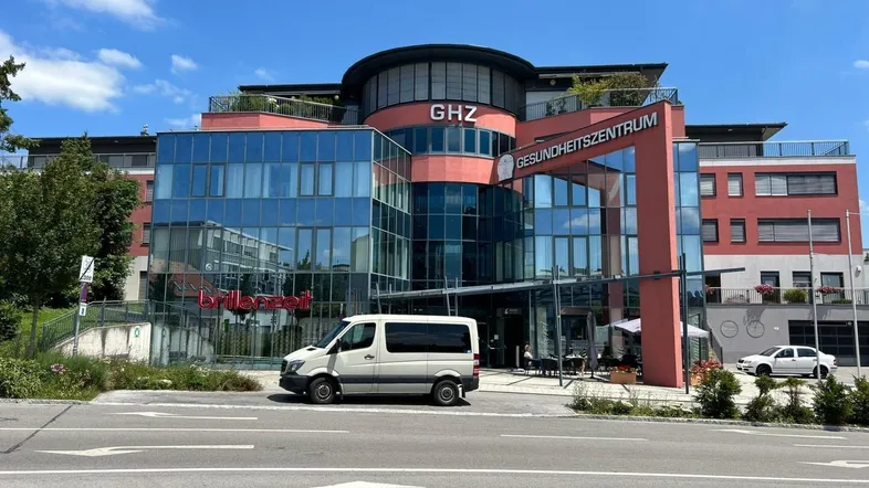 Modernes Gesundheitszentrum mit Glasfassade und mehreren Etagen unter blauem Himmel.