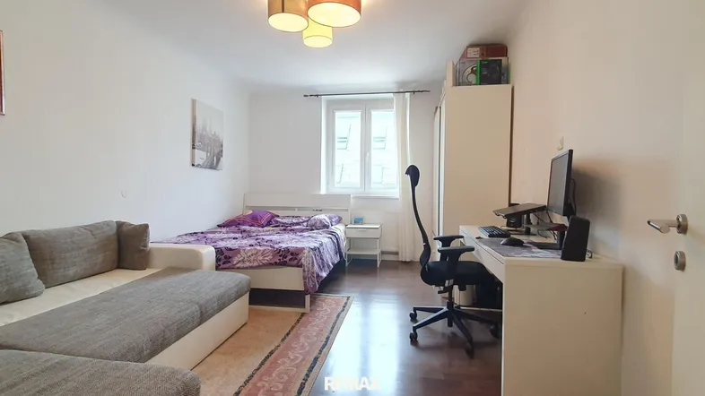 Helles Schlafzimmer mit Bett, Sofa und Schreibtisch, ideal für Studenten oder Singles.