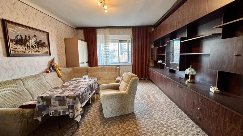 Geräumiges Wohnzimmer mit Teppichboden, großer Schrankwand und traditioneller Einrichtung.