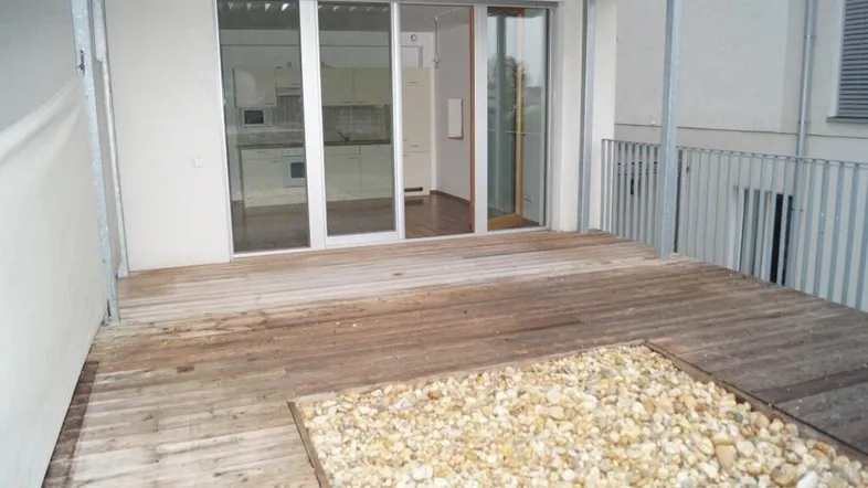 Geräumige Terrasse mit Holzdeck und Schiebetüren, die zu einem modernen Innenraum führen.