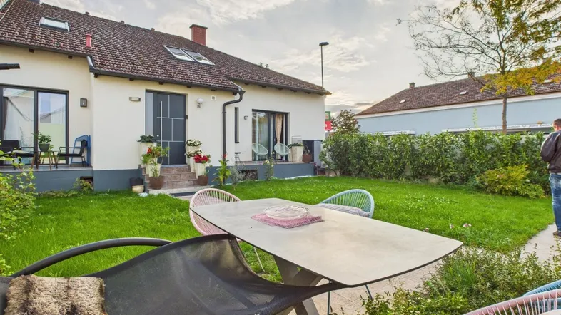 Großer Gartenbereich hinter dem Haus mit Rasenfläche und Sitzgelegenheiten für entspannte Stunden im Freien.