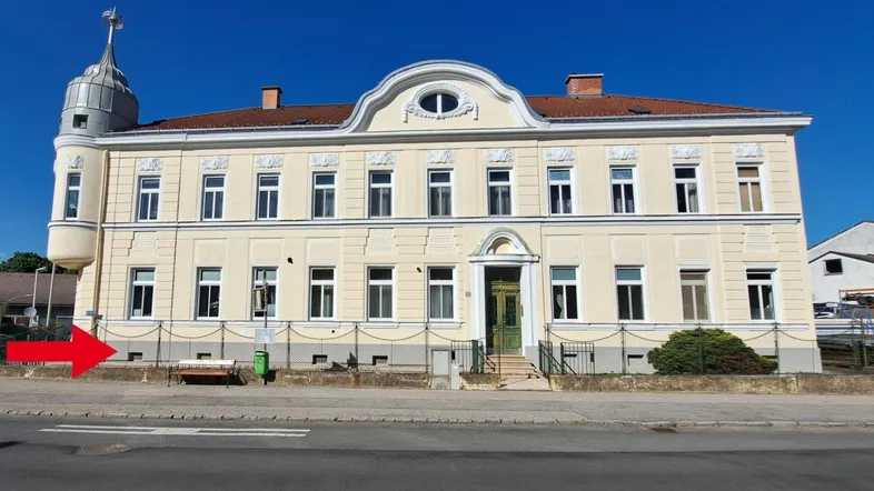 Historisches Gebäude mit klassischer Fassade, vielen Fenstern und einem markanten Eckturm unter blauem Himmel.