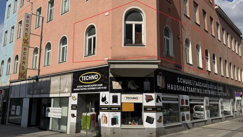 Gebäudeansicht eines Eckhauses mit Geschäftsflächen im Erdgeschoss und Wohnungen darüber.