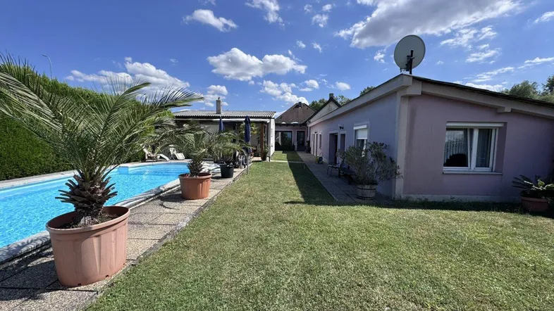 Großer Außenbereich mit Swimmingpool, Rasenfläche und Palmen vor dem Wohnhaus.