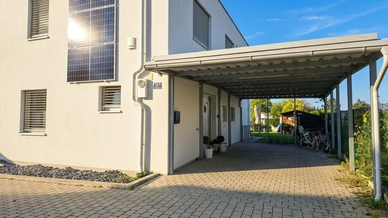 Modernes Haus mit Photovoltaikanlage an der Fassade und überdachtem Carport.