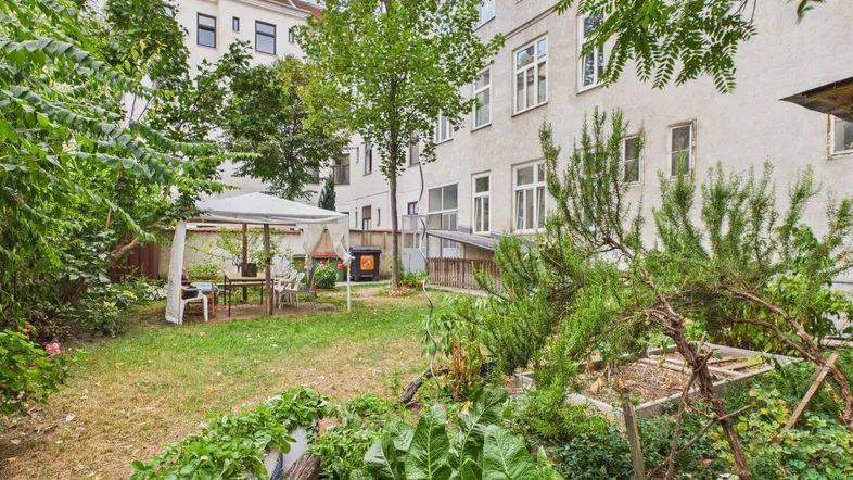 Grüner Hinterhofgarten mit Pavillon, Sitzgelegenheiten und verschiedenen Pflanzen für den Anbau.