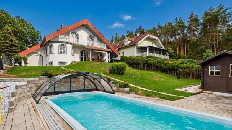 Großzügiger Außenbereich mit Pool und Blick auf das charmante Wohnhaus in grüner Umgebung.